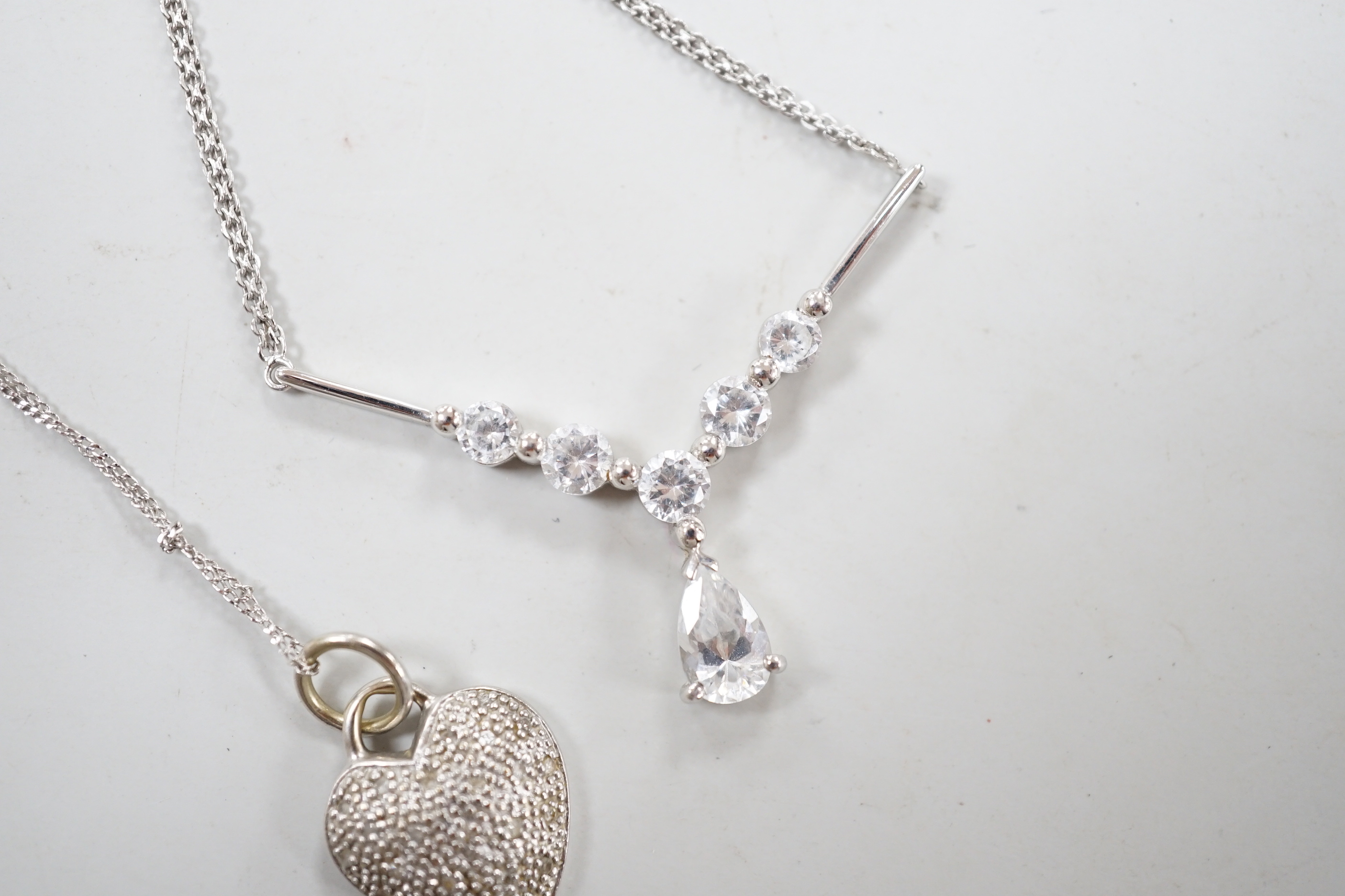 Two modern white metal (stamped 375) and gem set pendant necklaces, including a diamond chip set heart, longest 50cm